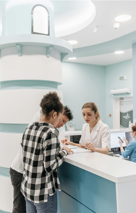 Patient consulting with healthcare receptionist about prior authorization paperwork at modern medical clinic